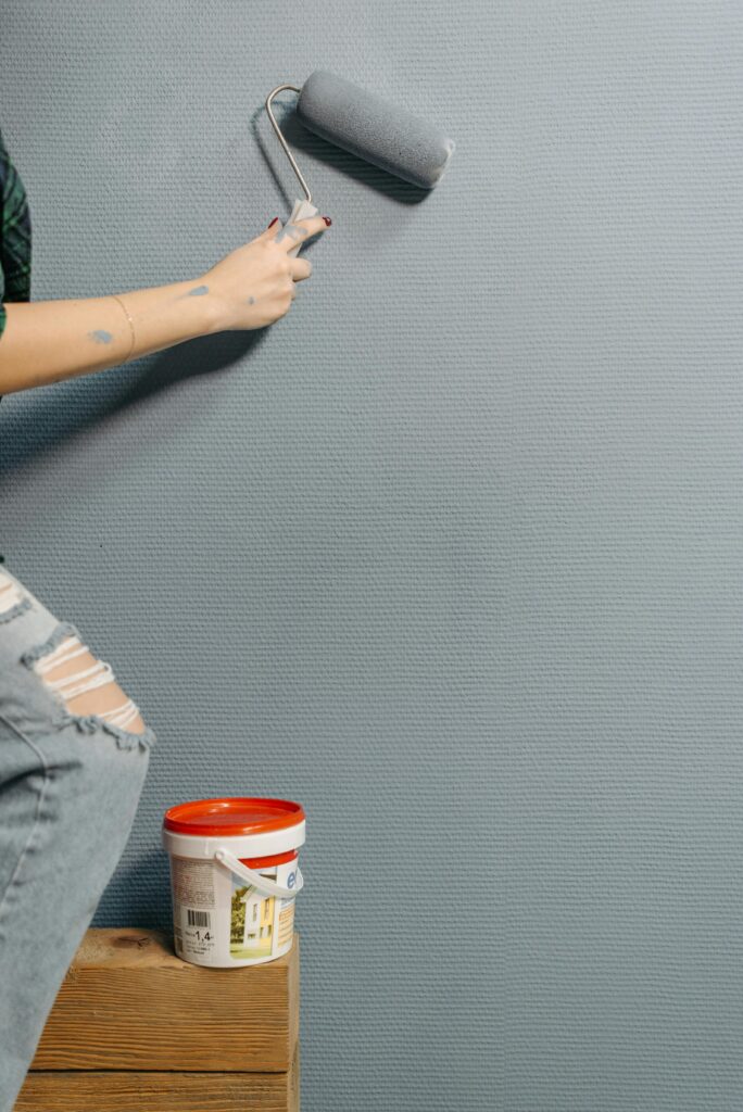 An adult painting a textured wall with a paint roller during home renovation.